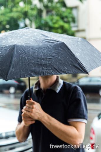 Mann mit Regenschirm im Regen