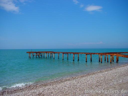 Foto von einem Strand aus Kies mit einem Steg zum gratis download