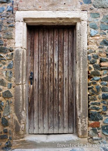Alte verwitterte Holztür in einer Steinmauer