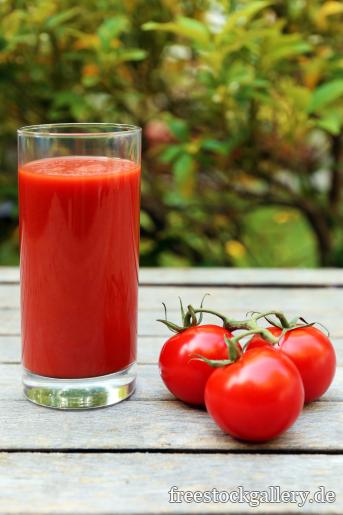 Tomatensaft und frische rote Tomaten im Garten