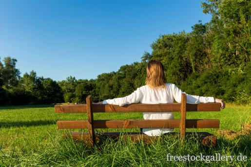 Frau sitzt auf einer Bank in der Natur