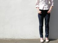 Frau in Jeans steht an einer Wand - kostenloses Bild
