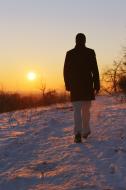 Mann spaziert im Schnee in den Sonnenuntergang - gratis Bild 