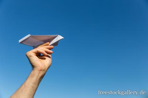 Papierflieger aus der Hand werfen - blauer Himmel